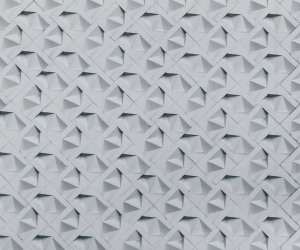 Textured wall showcasing a geometric 3D pattern in monochrome tones, perfect for architectural inspiration.
